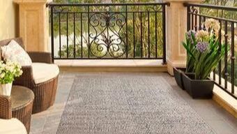 Terrace in a villa in Sotogrande with two armchairs, outdoor carpet, pots with flower plants and classic iron veranda