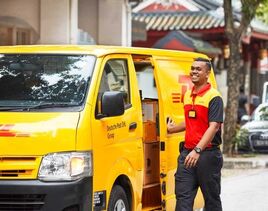 Yellow DHL delivery van with an smiling worker