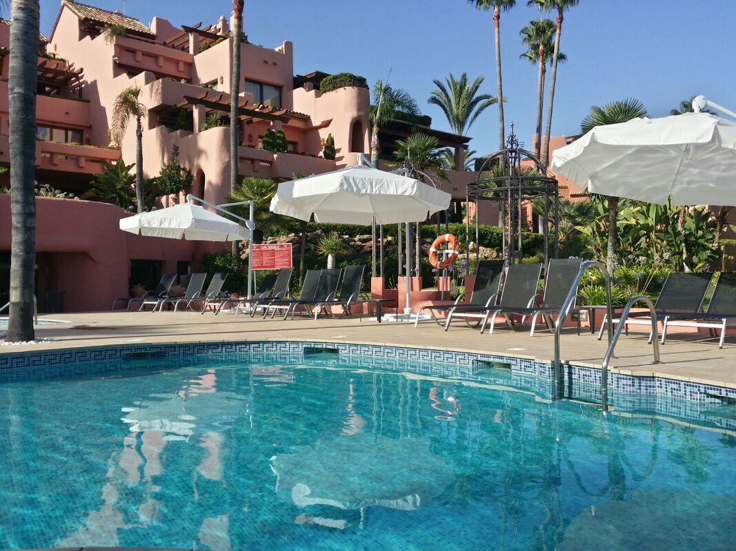 Umbrellas and parasols with sunloungers in community properties in Estepona