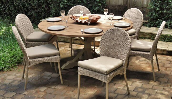 GARDEN SET OF ROUND TEAK TABLE WITH SIX CHAIRS IN CLASSIC STYLE AND PLATES, GLASS CUPS AND CUTLERY IN A GREEN LEAVED GARDEN IN sOTOGRANDE