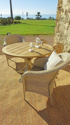 Round extendable table in wood and aluminium combined with cosy all-weather armchairs in La costa de la luz