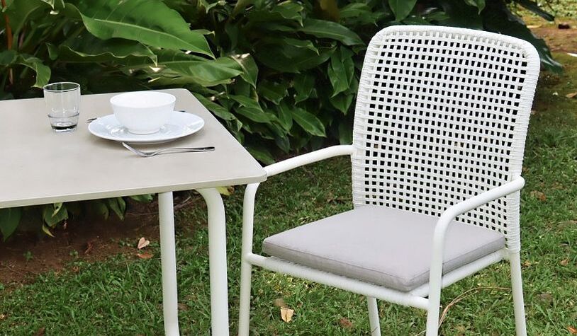 White rope weaved dining armchair with concrete top modern table in a green mature ttropical garden in Marbella, Malaga, Costa del Sol, Andalucia, Spain