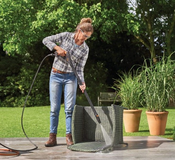 Woman cleaning a fibre garden chair with a Karcher cleaner.Picture
